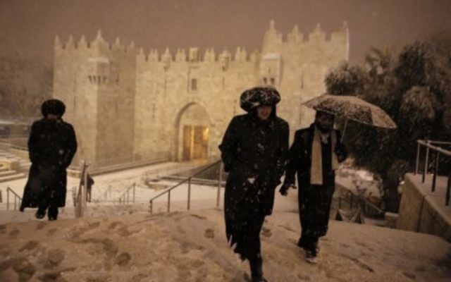 Des ultras-Orthodoxes marchant sous la neige près de la porte de Damas à Jérusalem le 19 février 2015 (Crédit : AFP PHOTO/AHMAD GHARABLI)