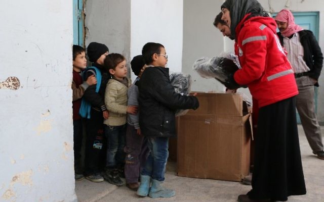Des membres du Croissant rouge syrien distribuant des vivres à des enfants le 21 février 2015 à Alep (Crédit : AFP PHOTO / BARAA AL-HALABI) Des membres du Croissant rouge syrien distribuant des vivres à des enfants le 21 février 2015 à Alep (Crédit : AFP PHOTO / BARAA AL-HALABI)