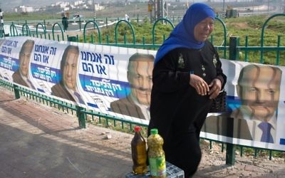 Une vendeuse palestinienne vendant de l'huile d'olive devant des affiches de campagne de Netanyahu le 10 mars 2015 à Givat Zeev, une implantation dans le nord de Jérusalem (Crédit : AFP/MENAHEM KAHANA)