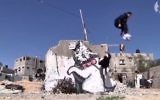 Des traceurs de parkour de Gaza sautant devant un graffiti de l'artiste britannique Banksy dans leur ville. (Capture d'écran: Youtube/The Guardian)