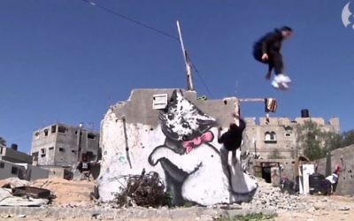 Des traceurs de parkour de Gaza sautant devant un graffiti de l'artiste britannique Banksy dans leur ville. (Capture d'écran: Youtube/The Guardian)