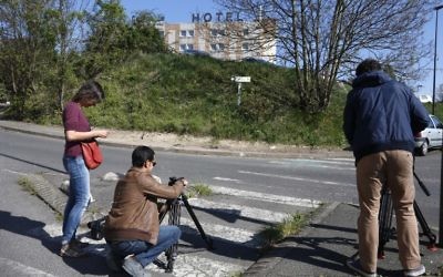 Des journalistes filment le site où le corps d'une femme avec trois blessures par balles a été retrouvé dans une voiture en feu à Villejuif, dans la banlieue sud de Paris, le 19 avril 2015. Les pompiers, prévenus par des passants qui ont vu la voiture en feu, sont arrivés sur les lieux et ont retrouvé le corps sans vie d'une femme âgée d'une trentaine d'année sur le siège passager à l'avant de la voiture en feu. La cause du décès n'a pas encore été établie. (Crédit : AFP PHOTO / FRANCOIS GUILLOT)