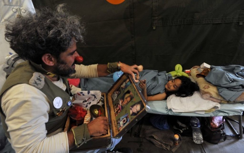Un clown 'médical' israélien divertit une victime du tremblement de terre du Népal lors d'une visite dans un camp de l'armée de fortune à Katmandou le 6 mai 2015. Le tremblement de terre de magnitude 7,8 qui a frappé la nation himalayenne le 25 avril 2015 et a eu un impact dévastateur sur l'économie du Népal où le tourisme a attiré près de 800 000 visiteurs étrangers en 2013 (Crédit : AFP PHOTO / PRAKASH MATHEMA) Un clown 'médical' israélien divertit une victime du tremblement de terre du Népal lors d'une visite dans un camp de l'armée de fortune à Katmandou le 6 mai 2015. Le tremblement de terre de magnitude 7,8 qui a frappé la nation himalayenne le 25 avril 2015 et a eu un impact dévastateur sur l'économie du Népal où le tourisme a attiré près de 800 000 visiteurs étrangers en 2013 (Crédit : AFP PHOTO / PRAKASH MATHEMA)
