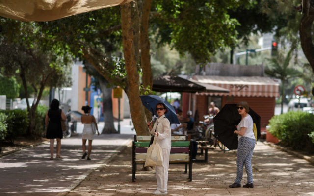 Des Israéliens utilisent des parapluies pour conjurer le fort soleil d'été sur le Boulevard Rothschild au centre  de Tel Aviv pendant une forte vague de chaleur qui a frappé le pays le 27 mai 2015  (Crédit photo: Ben Kelmer / Flash90)