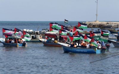 Les Palestiniens brandissent leur drapeau national lors d'un rassemblement pour montrer leur soutien aux militants à bord d'une flottille qui mettent le voile pour Gaza pour tenter de briser le blocus israélien sur Gaza, dans le port de Gaza ville, le 24 juin 2015 (Crédit : AFP / Mahmud Hams)