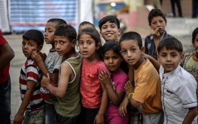 De jeunes enfants de réfugiés syriens font la queue pour la nourriture pour rompre le jeûne le 20 juin 2015 à Akcakale, dans la province de Sanliurfa, pendant le mois sacré du Ramadan. (Crédit : AFP)