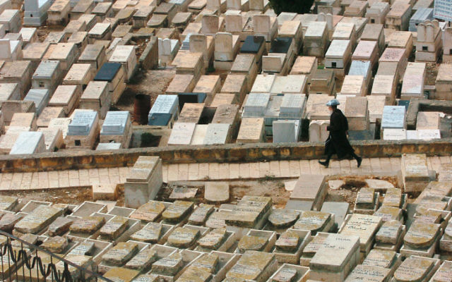 Un homme se promène dans un cimetière, à Jérusalem. (Crédit : Nati Shohat / Flash90)
