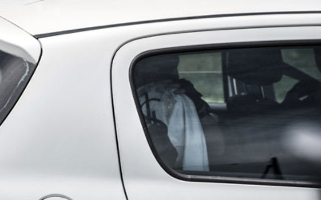 Le présumé suspect se couvrant la tête dans une voiture de police. (Crédit : Agence France-Presse) Le présumé suspect se couvrant la tête dans une voiture de police. (Crédit : Agence France-Presse)