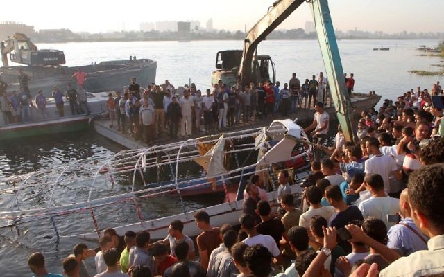 Les membres des familles des victimes et les spectateurs se rassemblent sur la rive du Nil le 23 juillet 2015, au nord de la capitale égyptienne du Caire, alors que l'épave d'un bateau est retiré hors de l'eau. Le bateau a coulé quand un cargo a frappé, tuant au moins 21 personnes personnes célébrant un engagement à bord (Crédit : AFP PHOTO / STR)