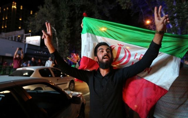 Un Iranien fait le signe de la victoire tandis qu'un autre tient le drapeau national iranien lors des célébrations de la signature de l'accord nucléaire dans le nord de Téhéran, le 14 juillet 2015 (Crédit : ATTA KENARE/ AFP) Un Iranien fait le signe de la victoire tandis qu'un autre tient le drapeau national iranien lors des célébrations de la signature de l'accord nucléaire dans le nord de Téhéran, le 14 juillet 2015 (Crédit : ATTA KENARE/ AFP)
