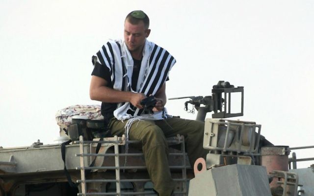 Un soldat de Tsahal prie au sommet d'un bulldozer blindé de Tsahal près de la frontière de Gaza dans le sud d'Israël, le premier jour de l'opération Bordure protectrice le 8 juillet 2014 (Crédit : David Buimovitch / Flash90) Un soldat de Tsahal prie au sommet d'un bulldozer blindé de Tsahal près de la frontière de Gaza dans le sud d'Israël, le premier jour de l'opération Bordure protectrice le 8 juillet 2014 (Crédit : David Buimovitch / Flash90)