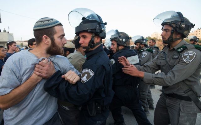 Les forces de sécurité israéliennes affrontant les résidents des implantations qui se sont barricadés pour tenter d'empêcher la démolition des bâtiments construits illégalement dans l'implantation juive de Beit El  le 28 juillet 2015 (Crédit : Nati Shohat / FLASH90)