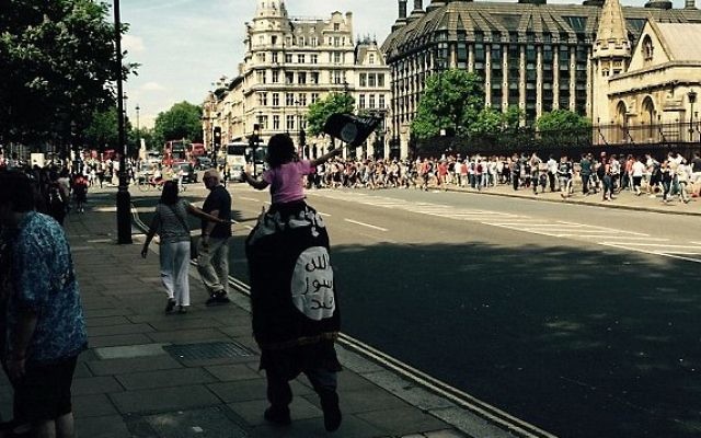 Un homme non identifié est repéré par des touristes en train de marcher à Londres enveloppé dans un drapeau de l'Etat islamique, portant un enfant agitant aussi le drapeau, Juillet 2015 (Photo: Twitter) Un homme non identifié est repéré par des touristes en train de marcher à Londres enveloppé dans un drapeau de l'Etat islamique, portant un enfant agitant aussi le drapeau, Juillet 2015 (Photo: Twitter)