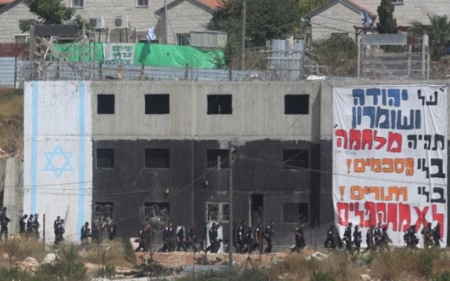 Les forces de sécurité israéliennes encerclent un bâtiment dans lequel des activistes se sont barricadés pour résister à son évacuation dans l'implantation de Beit El en Cisjordanie le 28 juillet 2015 (Crédit photo: Flash90)