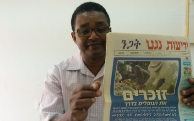 Dr Anbessa Teferra, professeur de langues sémitiques à l'université de Tel-Aviv, tient un numéro de Yedioth Negat, journal en amharique. (Ilan Ben Zion / Times of Israel)
