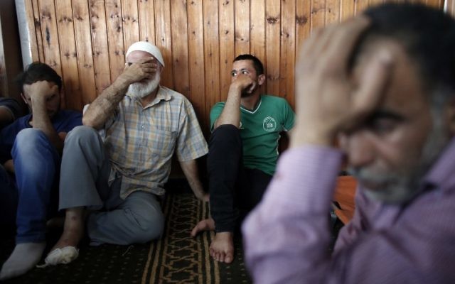 Les proches du bébé palestinien Ali Saad Dawabsha, tué après que sa maison a été incendiée, apparemment par des habitants des implantations juifs, en deuil à côté de son corps gisant dans une mosquée lors de ses funérailles dans le village cisjordanien de Douma le 31 juillet 2015. Hussein Dawabsha, le grand-père du bébé est visible sur la droite. (AFP PHOTO / THOMAS COEX)
