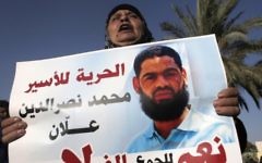 Maazouze, la mère de Mohammed Allaan, un prisonnier palestinien avait fait une grève de la faim à long terme, porte un portrait de son fils lors d'un rassemblement appelant à sa libération dans la ville israélienne de Beer Sheva, le 9 août 2015 (Crédit photo: Ahmad Gharabli / AFP)