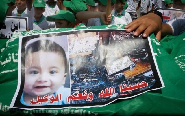Des enfants palestiniens portent un brancard funèbre avec une image du petit Ali Saad Dawabsha, l'enfant qui a été brûlé à mort par des extrémistes juifs, le 1er août, 2015, lors d'une manifestation à Khan Yunis, dans la bande de Gaza, simulant un enterrement organisée par les partisans palestiniens du Hamas en réaction à la mort du bébé (Crédit : Abed Rahim Khatib / flash 90)