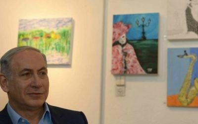 Le Premier ministre Benjamin Netanyahu visite une exposition de peintures d'Hadar Goldin, tombé dans une bataille à Gaza et dont le corps n'a pas été récupéré, au village d'artistes d'Ein Hod dans le nord d'Israël, le 10 août 2015. (Crédit : Amos Ben Gershom/GPO)