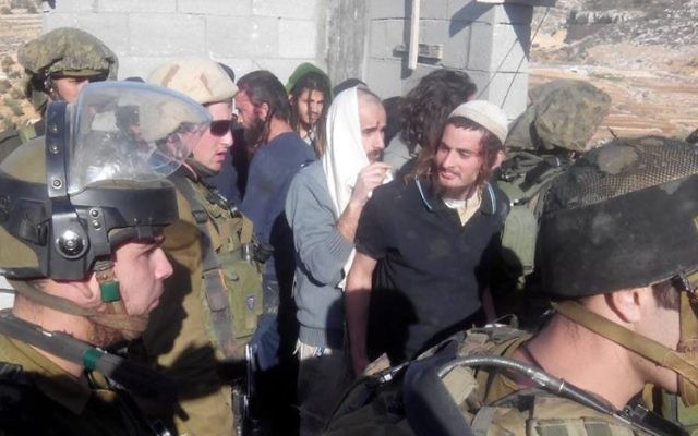 Meir Ettinger, en kippa blanche, escorté par des soldats de Tsahal dans le village Qusra en Cisjordanie, le 7 janvier 2014 (Crédit photo : Zacharia Sadeh/Rabbis for Human Rights)