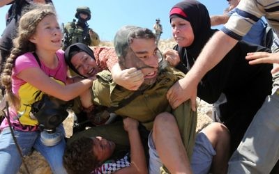 Des Palestiniens combattant un soldat israélien qui a tenté d'arrêter un garçon lors d'une manifestation près du village cisjordanien de Nabi Saleh, près de Ramallah, le 28 août 2015 (Crédit : AFP Photo / Abbas Momani)