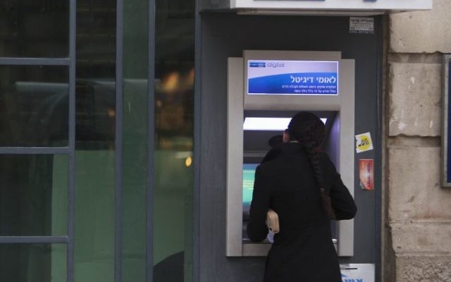 Une femme se tient devant un guichet automatique à Jérusalem (Crédit: Yonatan Sindel / Flash90)