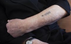 Un survivant de l'Holocauste montre son numéro de prisonnier tatoué sur son bras. (Crédit : Yonatan Sindel / Flash90)