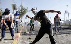 Des émeutiers palestiniens masqués jetant des pierres sur la police israélienne lors d'affrontements dans le quartier de Shuafat à Jérusalem-Est, le 3 juillet 2014 (Crédit photo: Sliman Khader / Flash90)