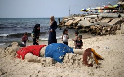 Des Palestiniennes ont mis des fleurs sur une sculpture de sable représentant le petit garçon syrien Aylan Kurdi, au large de la Turquie, le 7 septembre, 2015, à Gaza City Beach. (Crédit : AFP / MOHAMMED ABED)