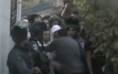 Les forces de sécurité israéliennes escortant cinq étudiants d'une yeshiva hors d'une maison palestinienne à Hébron le 3 août  2015, où ils s'étaient réfugiés après que leur présence dans la ville cisjordanienne ait déclenché des émeutes. (Crédit : Capture d'écran site Web NRG)