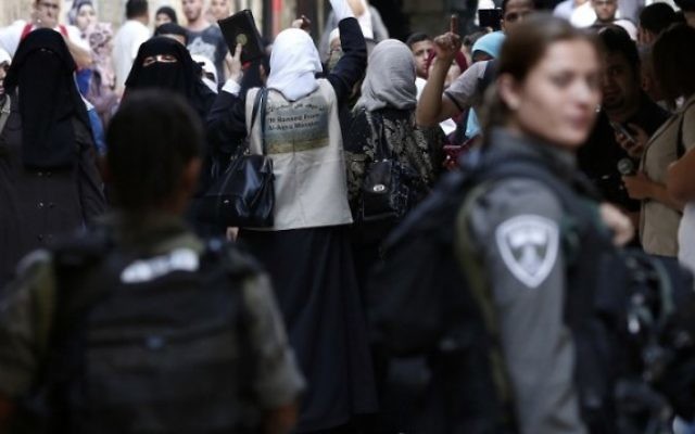 Des Palestiniennes criant des slogans devant les forces de sécurité israéliennes qui bloquent une rue menant au Mont du Temple, dans le quartier musulman de la Vieille Ville de Jérusalem, le 15 septembre 2015. (Credit photo: Thomas Coex / AFP)