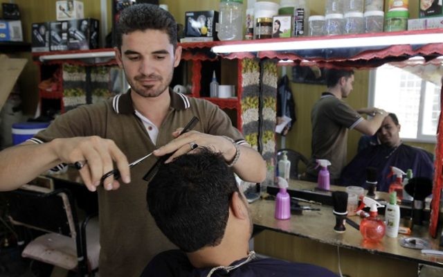 Coiffeur et artiste syrien, Mohamed Jokhadar, 29 ans, qui a fui la province de Homs en Syrie avec ses filles et sa femme, esquisse une image depuis son salon de coiffure improvisé situé sur la principale allée commerciale du camp de réfugiés de Zaatari, surnommée "Champs Elysée", le 30 septembre 2015 (Crédit : AFP PHOTO / KHALIL MAZRAAWI)