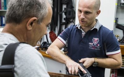 Un employé d'un armuriers et d'un stand dans la ville côtière israélienne de Tel Aviv montre une arme à un client le 13 Octobre 2015. La  récente vague de troubles entre les Palestiniens et les Israéliens, qui a vu une série d'attaques au couteau et des manifestations violentes ont soulevé des craintes d'un troisième soulèvement palestinien, ou Intifada (Crédit : AFP PHOTO / JACK GUEZ)