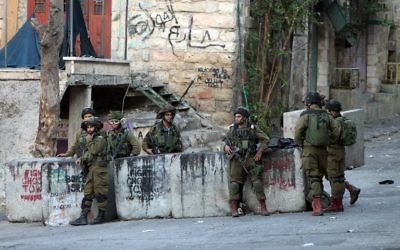 Les forces de sécurité israéliennes montent la garde près de l'endroit où un Palestinien a tenté de poignarder un soldat israélien avant d'être abattu, dans la ville d'Hébron en Cisjordanie, le mercredi 28 octobre 2015 (Crédit : AFP PHOTO / HAZEM BADER)