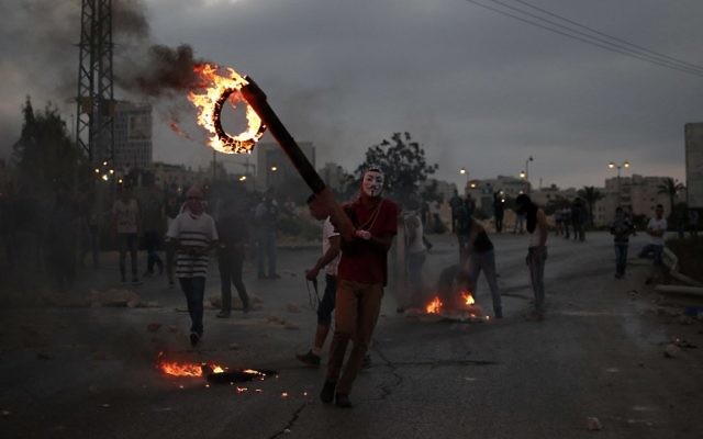 La jeunesse palestinienne en train de brûler des pneus lors d'affrontements avec des soldats israéliens près de l'implantation juive de Bet El, dans la ville de Ramallah en Cisjordanie, le 4 octobre 2015 (Crédit : Abbas Momani / AFP)