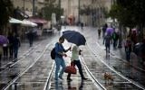 Des Israéliens avec leurs parapluies pour se protéger de la pluie tandis qu'ils marchent sur la rue de Jaffa, dans le centre de Jérusalem le 31 octobre 2014 (Crédit : Miriam Alster / Flash90)