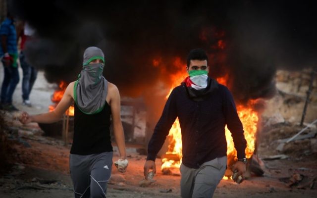 Des manifestants palestiniens jettent des pierres et brûlent des pneus lors d'affrontements avec les forces de sécurité israéliennes près du checkpoint de Hizma, en Cisjordanie, le 30 septembre 2015. Illustration. (Crédit : Flash90) Des manifestants palestiniens jettent des pierres et brûlent des pneus lors d'affrontements avec les forces de sécurité israéliennes près du checkpoint de Hizma, en Cisjordanie, le 30 septembre 2015. Illustration. (Crédit : Flash90)