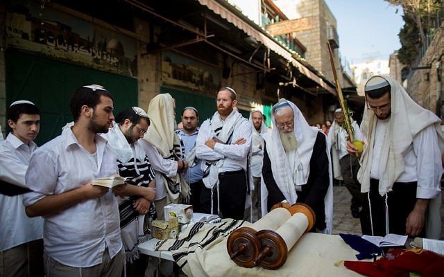 Des hommes prient sur le lieu de l'attaque où deux Israéliens ont ét tués par un terroriste palestinien la veille (Crédit : Flash 90)
