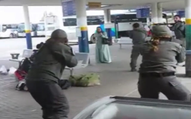 Une image prise d'un téléphone portable des images des forces de sécurité entourant une femme arabe israélienne brandissant un couteau après avoir prétendument tenté de poignarder un garde de sécurité à la gare routière d'Afula, le vendredi 9 octobre 2015. (Crédit : Capture d'écran) Une image prise d'un téléphone portable des images des forces de sécurité entourant une femme arabe israélienne brandissant un couteau après avoir prétendument tenté de poignarder un garde de sécurité à la gare routière d'Afula, le vendredi 9 octobre 2015. (Crédit : Capture d'écran)