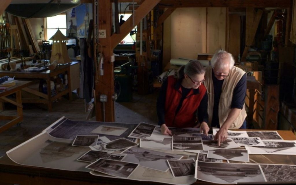 Les artistes Rick et Laura Brown examinant les photos des synagogues polonaises qui n'existent plus pour aider à la reconstruction de la synagogue Gwoździec (Crédit : Trillium Studios production)