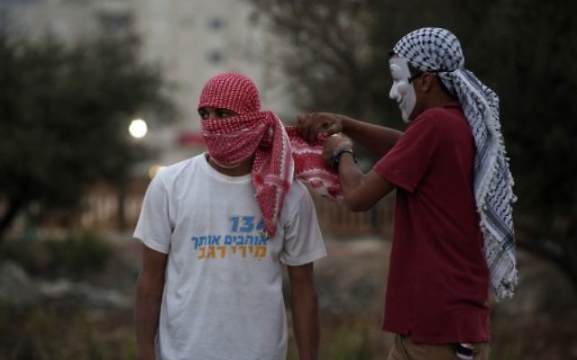 Un jeune Palestinien portant un ancien t-shirt de la campagne pour les primaires du Likud de la ministre de la Culture Miri Regev lors d'affrontements avec l'armée israélienne dans la ville de Ramallah en Cisjordanie, le 4 ioctobre 2015 (Crédit photo: Abbas Momani / AFP)