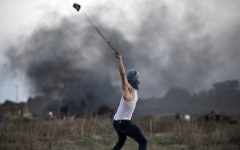 Un émeutier palestinien utilise un lance-pierre pour jeter des pierres sur des soldats israéliens lors d'affrontements, près de la barrière de sécurité entre Israël et la bande de Gaza, le 15 octobre 2015. Illustration. (Crédit : Mohammed Abed/AFP)