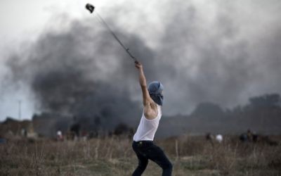 Un émeutier palestinien utilise un lance-pierre pour jeter des pierres sur des soldats israéliens lors d'affrontements, près de la barrière de sécurité entre Israël et la bande de Gaza, le 15 octobre 2015. Illustration. (Crédit : Mohammed Abed/AFP)