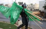 Un membre des forces de sécurité israéliennes porte  des drapeaux de l'organisation terroriste du Hamas qui ont été saisis lors d'affrontements avec des manifestants palestiniens près de limplantation de Beit El en Cisjordanie, le 8 octobre 2015 (Credit photo: Abbas Momani / AFP)