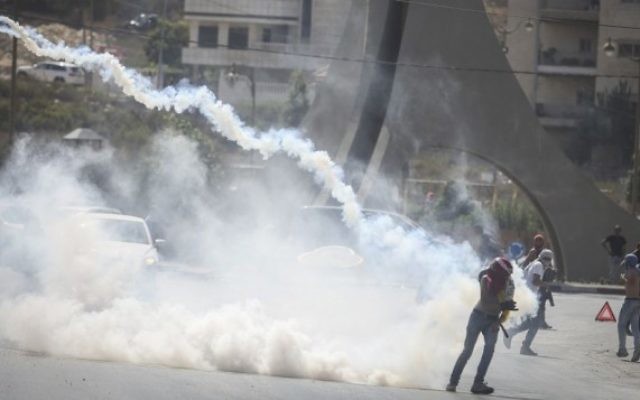 Des manifestants palestiniens courent pour échapper à des gaz lacrymogènes lors d'affrontement avec la police après une manifestation dans la ville de Ramallah en Cisjordanie, le 5 octobre 2015 (Crédit photo: Flash90)