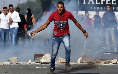 Un manifestant palestinien jette une cartouche de gaz lacrymogène lors d'affrontements avec les soldats israéliens au checkpoint de Hawara, au sud de la ville de Naplouse en Cisjordanie, le 9 octobre 2015 (Crédit photo: JAAFAR ASHTIYEH / AFP)