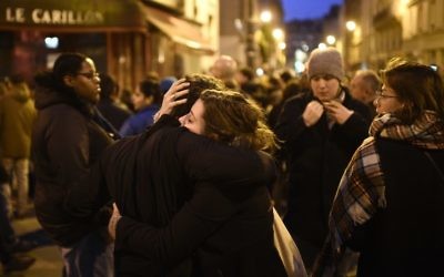 Rassemblement près du restaurant Le Carillon, l'un des sites des attentats à Paris, le 14 novembre 2015. Au moins 128 personnes ont été tuées dans les attentats de Paris qui ont eu lieu pendant la soirée du 13 novembre, avec 180 personnes blessées (Crédit : Martin Bureau/AFP)