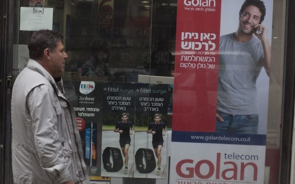 Un homme marchant à côté d'une affiche de publicité pour Golan Telecom à Jérusalem, le 5 novembre 2015. (Crédit : Lior Mizrahi / Flash90) Un homme marchant à côté d'une affiche de publicité pour Golan Telecom à Jérusalem, le 5 novembre 2015. (Crédit : Lior Mizrahi / Flash90)