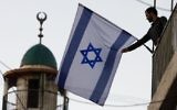 Un Israélien juif avec le drapeau d'Israël près de la Vieille Ville de Jérusalem (Crédit : Abir Sultan / flash 90)