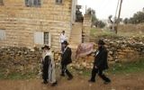 Des Juifs ultra-orthodoxes passent devant une maison palestinienne fouillée par des soldats israéliens dans la ville de Hébron en Cisjordanie, le 7 novembre 2015 (Crédit photo: Hazem Bader / AFP)